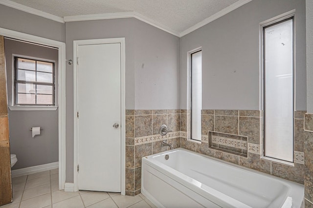 bathroom featuring a textured ceiling, tile patterned flooring, toilet, a bath, and crown molding