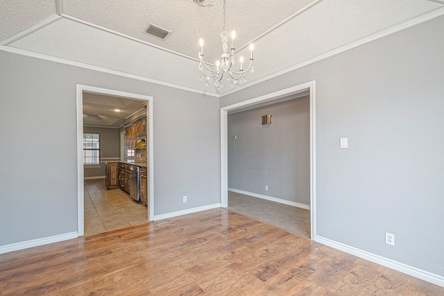 empty room with crown molding, light wood finished floors, and a notable chandelier