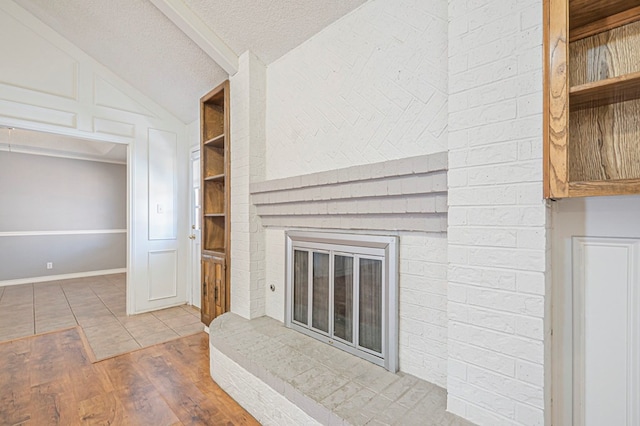 unfurnished living room with built in shelves, a fireplace, lofted ceiling, a textured ceiling, and wood finished floors