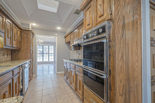 kitchen featuring brown cabinets, tasteful backsplash, stainless steel appliances, and light tile patterned flooring