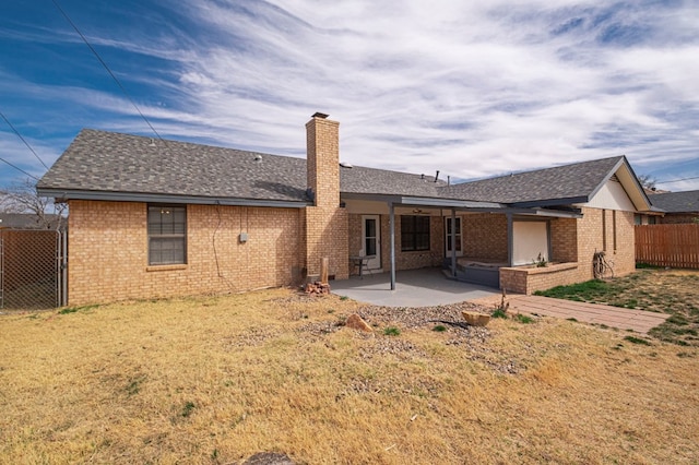 back of property with a patio, brick siding, fence, a yard, and a chimney