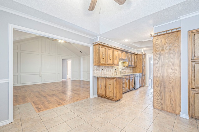 kitchen with light tile patterned flooring, a decorative wall, ornamental molding, stainless steel dishwasher, and backsplash