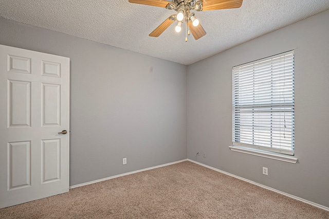 carpeted spare room with a textured ceiling, ceiling fan, and baseboards