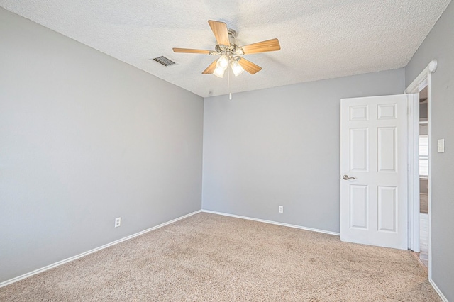 carpeted empty room featuring a textured ceiling, baseboards, visible vents, and a ceiling fan