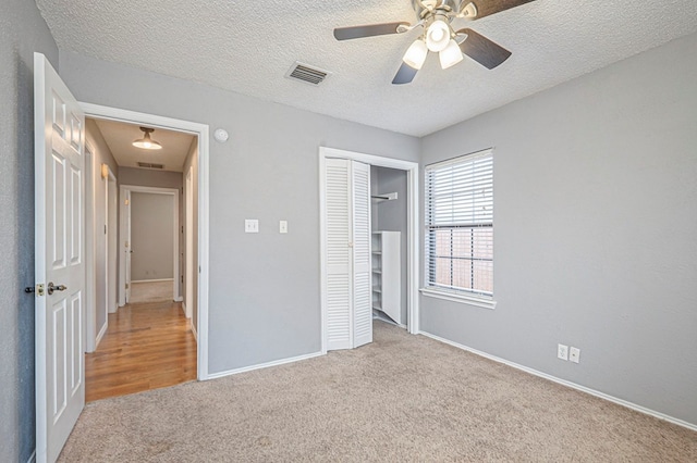 unfurnished bedroom with carpet floors, a closet, visible vents, a textured ceiling, and baseboards