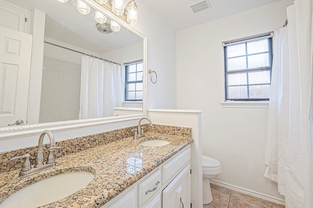 full bath with toilet, double vanity, visible vents, and a sink