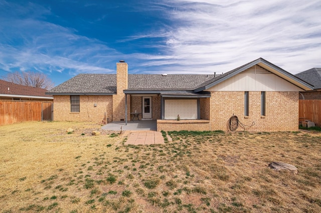 back of property with brick siding, a chimney, fence, and a patio