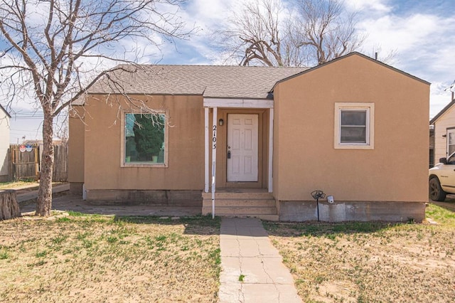 view of front of house featuring a shingled roof, fence, and stucco siding