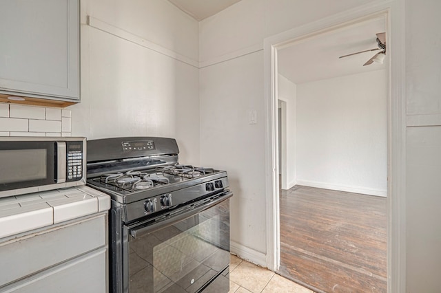 kitchen featuring tasteful backsplash, tile counters, ceiling fan, stainless steel microwave, and black gas stove