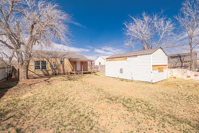 back of house featuring an outbuilding, a lawn, and fence