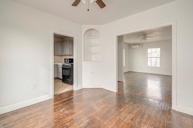 spare room featuring dark wood-type flooring, a ceiling fan, and baseboards