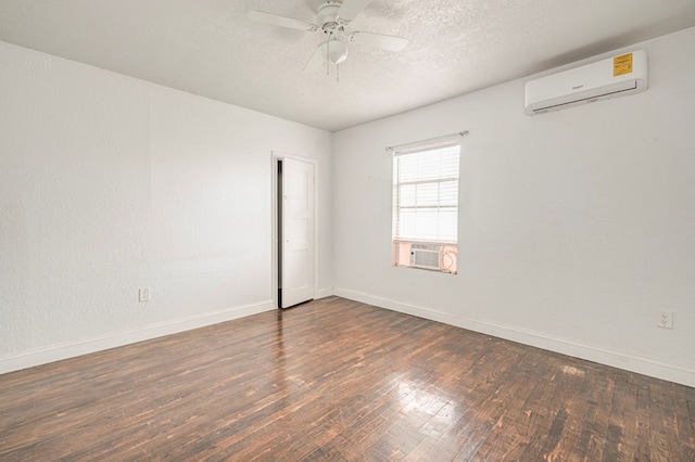 unfurnished room featuring a wall unit AC, hardwood / wood-style floors, a ceiling fan, a textured ceiling, and baseboards