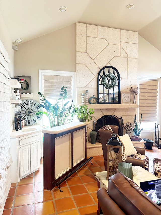 bar featuring light tile patterned floors, a fireplace, a sink, vaulted ceiling, and a wealth of natural light