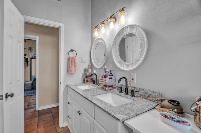 bathroom featuring double vanity, baseboards, tile patterned floors, and a sink