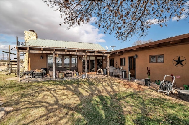 rear view of property with an outdoor fire pit, a yard, stucco siding, a chimney, and a patio area