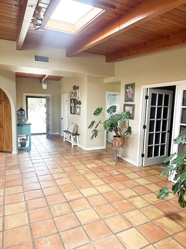 foyer entrance with light tile patterned floors, visible vents, a skylight, wood ceiling, and beamed ceiling