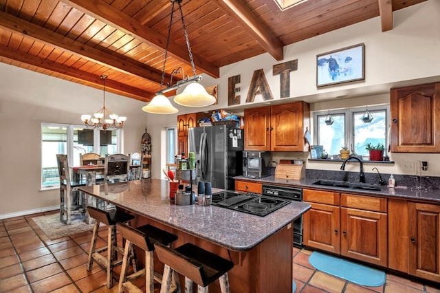 kitchen with a kitchen bar, stainless steel refrigerator with ice dispenser, a sink, a center island, and brown cabinetry