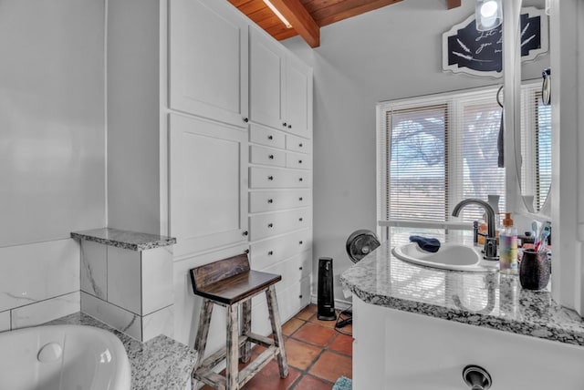 bathroom featuring tile patterned floors, beamed ceiling, vanity, and a tub to relax in