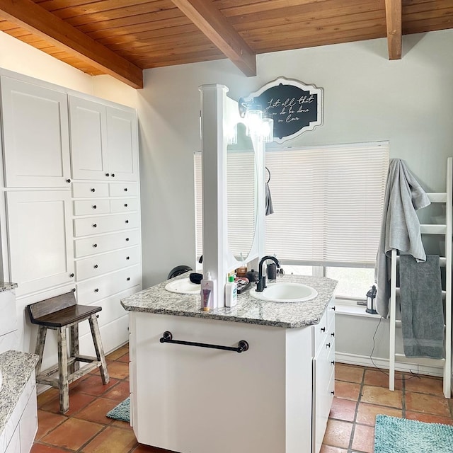 kitchen with beam ceiling, a sink, white cabinets, light stone countertops, and wood ceiling