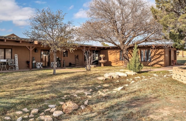 back of house with a yard and stucco siding