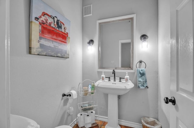 half bath with visible vents, toilet, and a sink