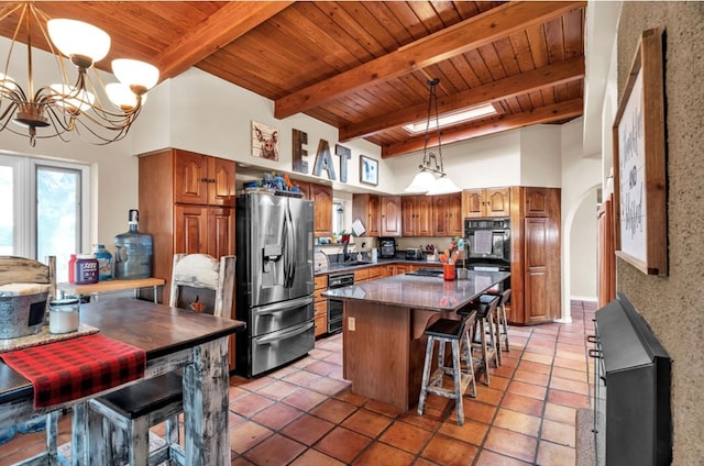 kitchen featuring stainless steel fridge, arched walkways, brown cabinetry, and a kitchen island