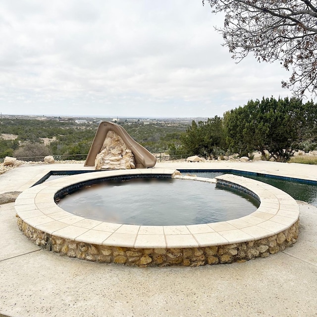 view of pool with an in ground hot tub and a water slide