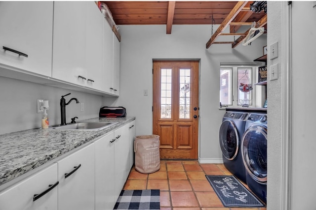 clothes washing area featuring a sink, washer and dryer, cabinet space, light tile patterned floors, and wood ceiling