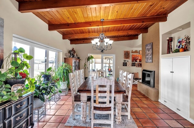 tiled dining space featuring a chandelier, beam ceiling, a fireplace, and wood ceiling