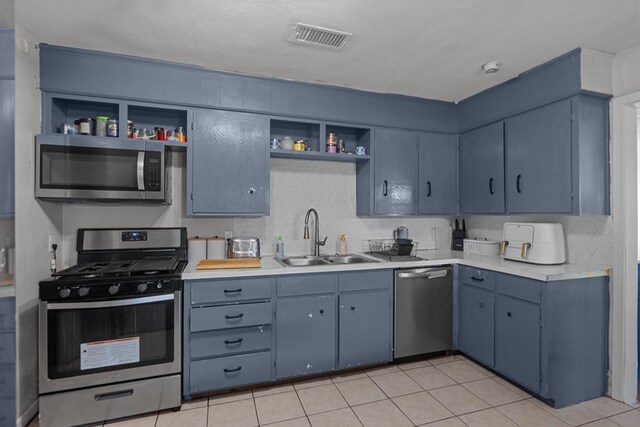 kitchen with blue cabinetry, appliances with stainless steel finishes, and sink