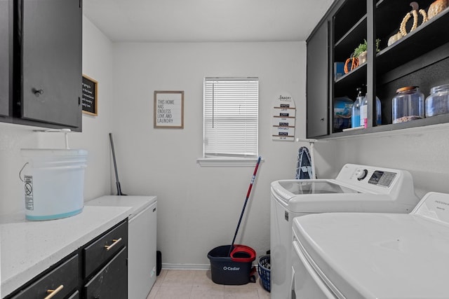 clothes washing area featuring cabinets, light tile patterned floors, and washing machine and clothes dryer