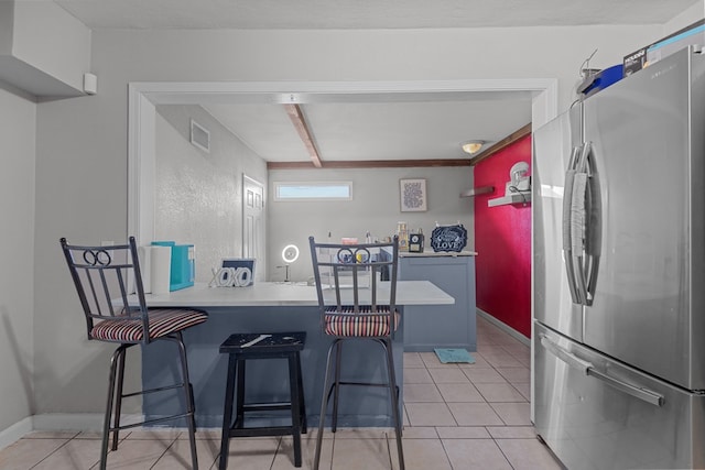 kitchen featuring a kitchen bar, kitchen peninsula, stainless steel fridge, and light tile patterned floors