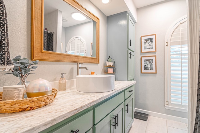 bathroom with baseboards, tile patterned flooring, a textured wall, and vanity