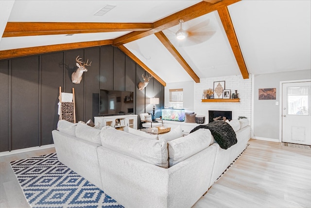 living area featuring lofted ceiling with beams, plenty of natural light, and light wood-style floors