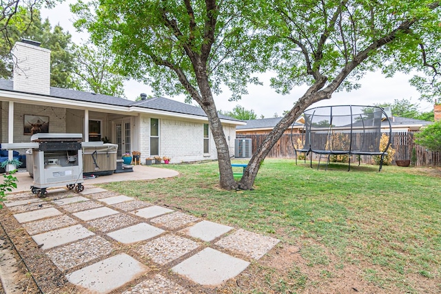 view of yard with a patio, a trampoline, a fenced backyard, and a hot tub