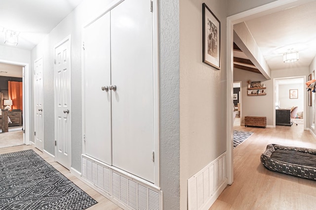 hall featuring wood finished floors, visible vents, and baseboards
