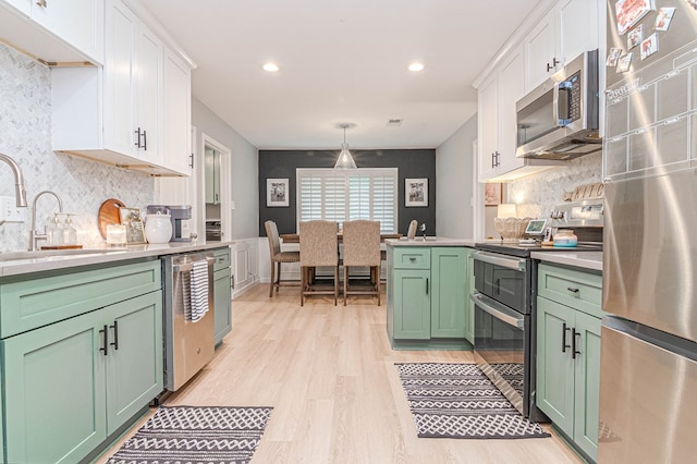 kitchen with green cabinetry, a sink, white cabinets, and stainless steel appliances