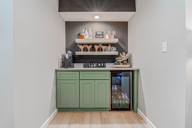 bar featuring beverage cooler, light wood-type flooring, a textured wall, and a dry bar