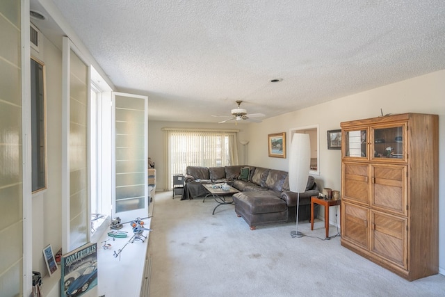 living area with ceiling fan, visible vents, a textured ceiling, and light colored carpet