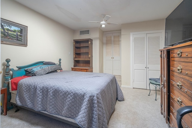 bedroom with light carpet, visible vents, baseboards, a ceiling fan, and two closets