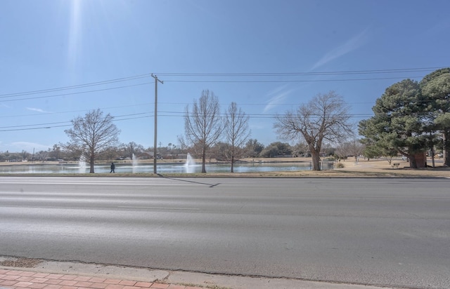 view of road with a water view, sidewalks, and curbs