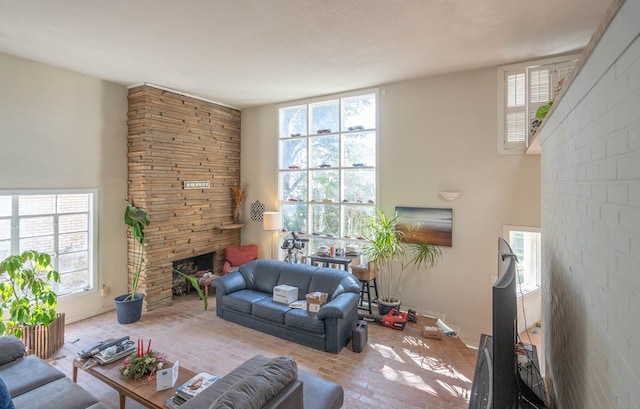 living room featuring brick floor, baseboards, and a stone fireplace