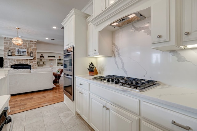 801 Keystone Ct, Midland, TX 79705 - kitchen featuring appliances with stainless steel finishes, white cabinets, a fireplace, light stone countertops, and recessed lighting