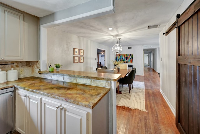2202 Princeton Ave, Midland, TX 79701 - kitchen featuring a peninsula, dishwasher, light wood-style floors, a barn door, and a chandelier