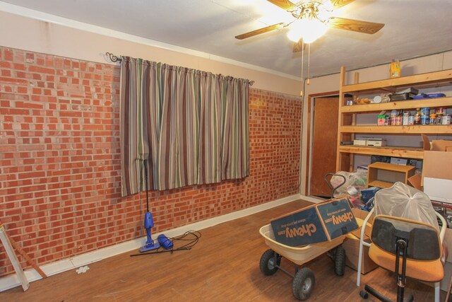 interior space with hardwood / wood-style flooring, ceiling fan, and brick wall