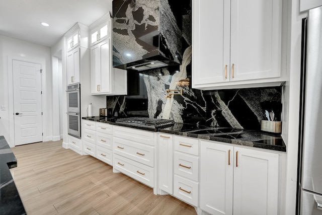 kitchen featuring extractor fan, stainless steel appliances, white cabinetry, decorative backsplash, and light wood finished floors