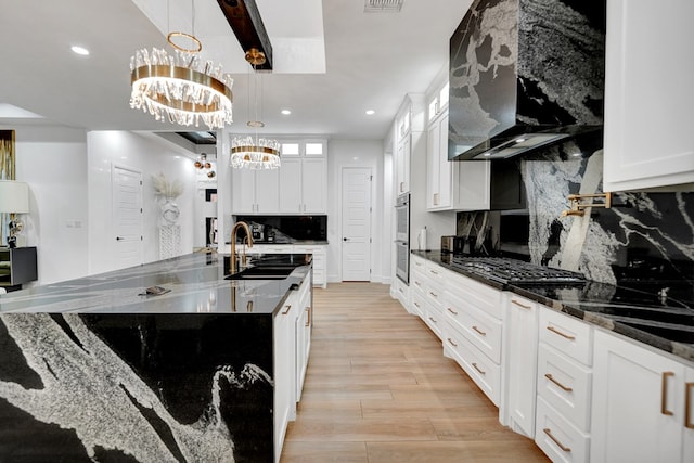 kitchen featuring tasteful backsplash, a sink, glass insert cabinets, and an inviting chandelier