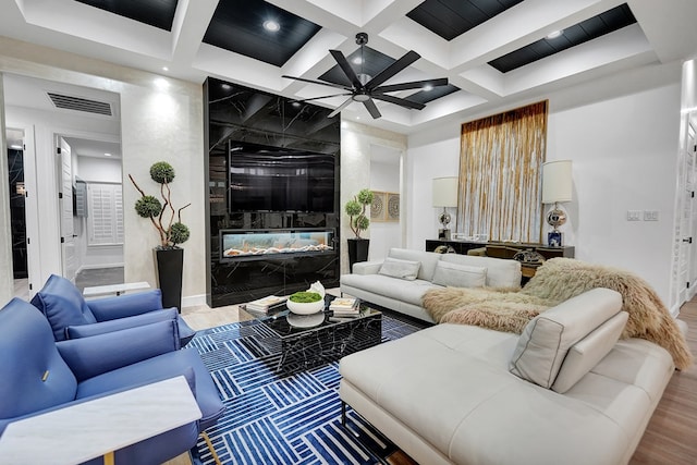 living area with beam ceiling, a fireplace, coffered ceiling, and visible vents