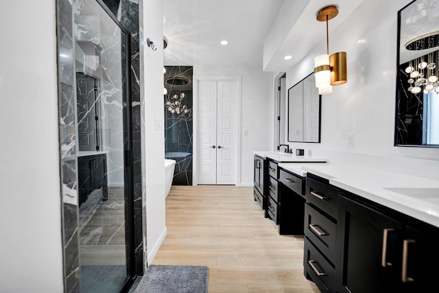 full bath with double vanity, wood finished floors, a freestanding tub, a shower stall, and recessed lighting