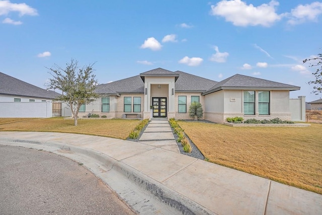 prairie-style home featuring a front yard, french doors, brick siding, and stucco siding